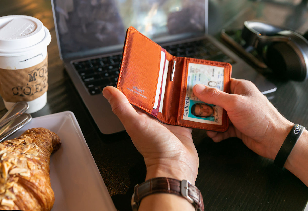 Photo of hands opening up a light brown wallet.