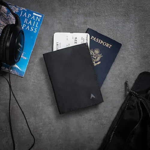 Photo shows a black vegan nylon wallet from Allett that has a passport sticking out and travel documents.