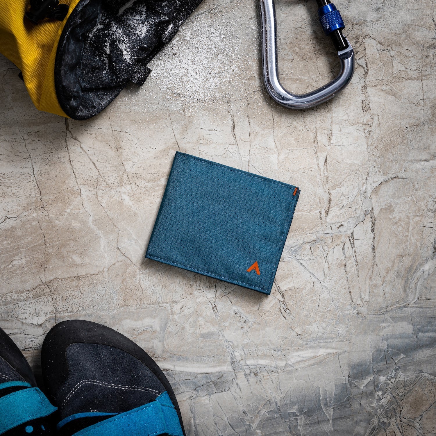 An indigo blue nylon vegan wallet on a table, surrounded by outdoor activity items - Allett ID Wallet Nylon RFID indigo-blue