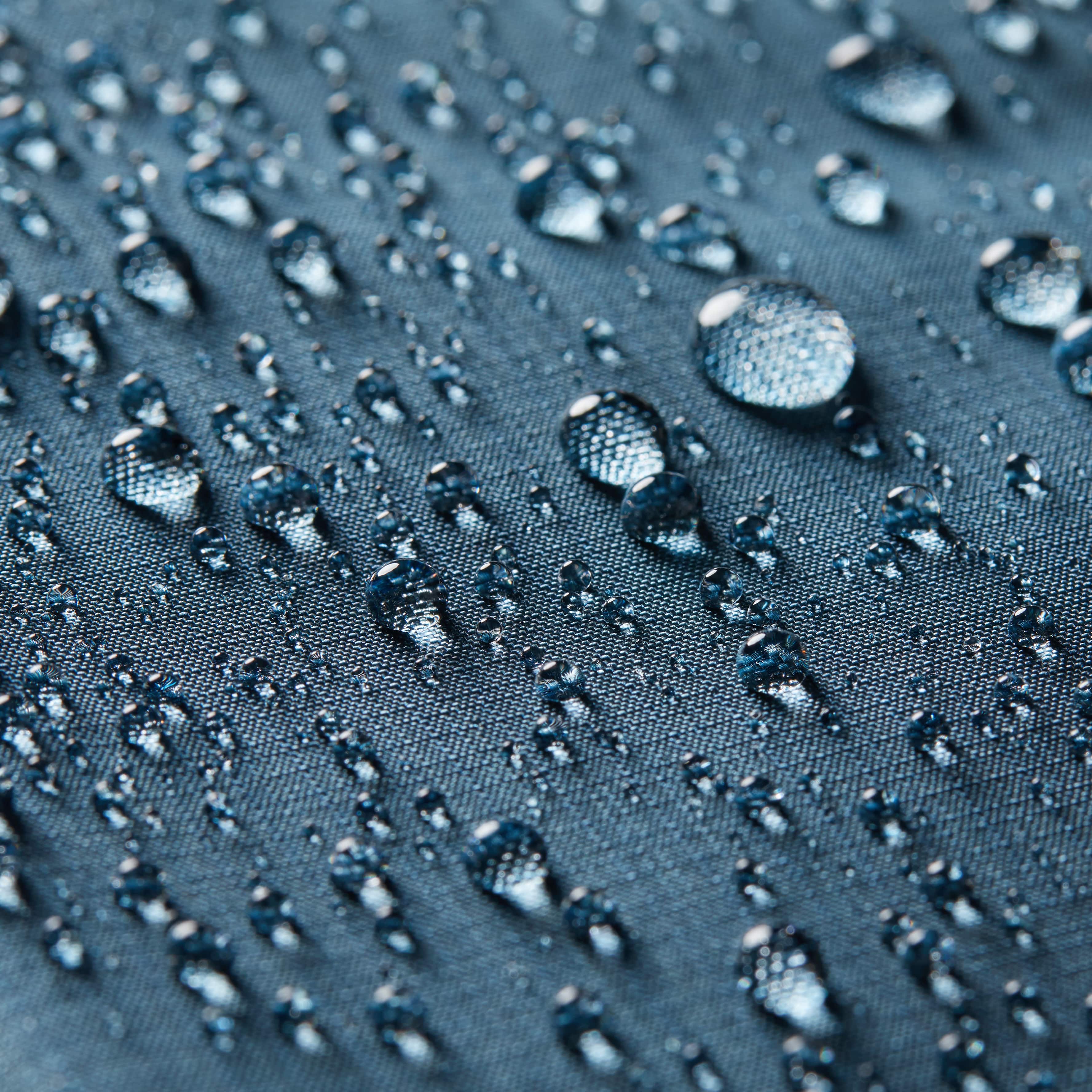 Conceptual picture highlighting water beads on the nylon surface of an indigo blue coin wallet, with the Allett logo faintly visible in orange. allett coin wallet 2.0 indigo-blue