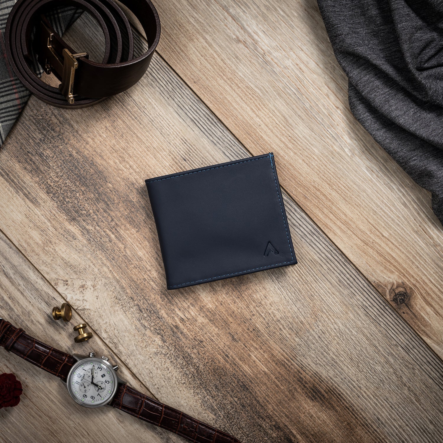 Allett's leather midnight blue ID wallet on a wood background surrounded by decorative items. Allett id wallet leather midnight-blue