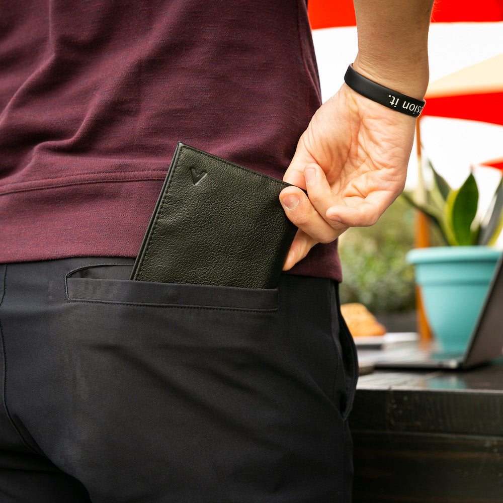 Individual inserting an onyx black leather coin wallet into black pants, wearing a maroon shirt. allett leather coin wallet onyxblack