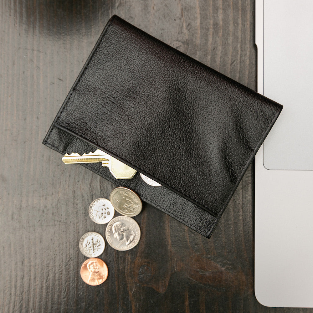 Coins and a key spilling out of the onyx black Nappa leather wallet from Allett.  allett leather coin wallet onyx-black