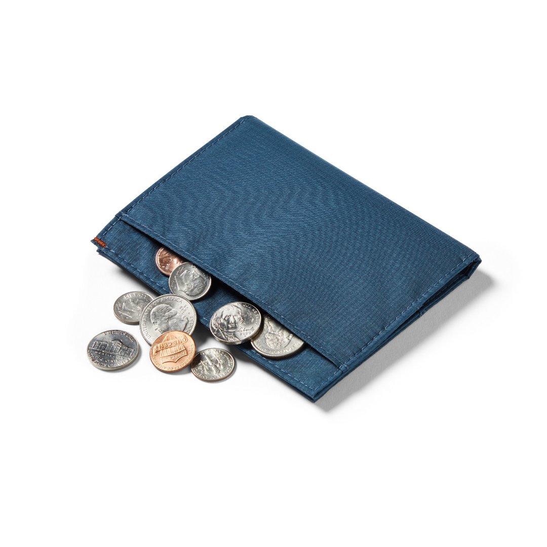 Allett's ripstop nylon vegan coin wallet placed down showing coins spilling out of the pocket of the wallet. allett coin wallet indigo-blue